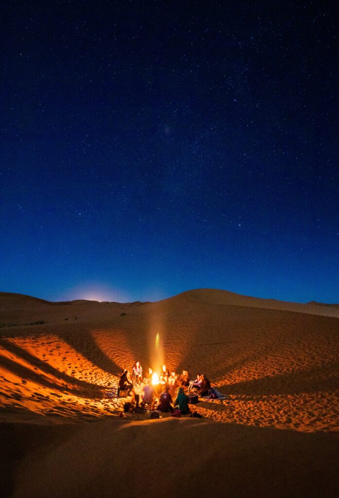 People sitting around a campfire at night in the Sahara desert